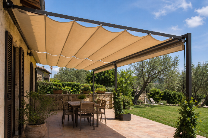 Pérgola de aluminio con techo retráctil de tejido Soltis impermeable sobre terraza con comedor exterior