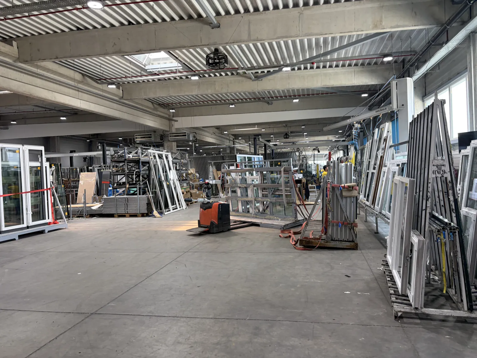 Nave de fabricación con marcos de ventanas organizados en soportes y equipos de trabajo