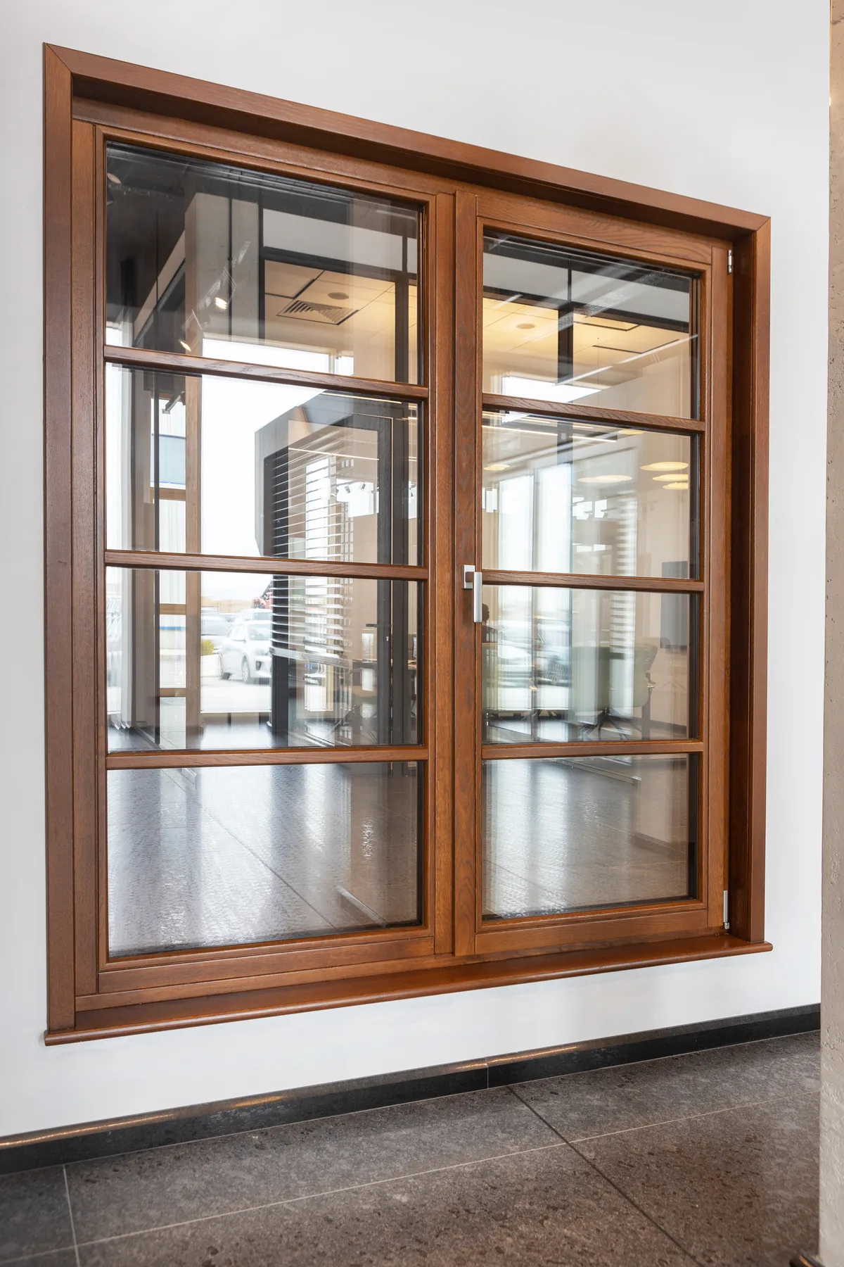 Ventana de madera con dos paños acristalados y divisiones horizontales en una exposición interior.